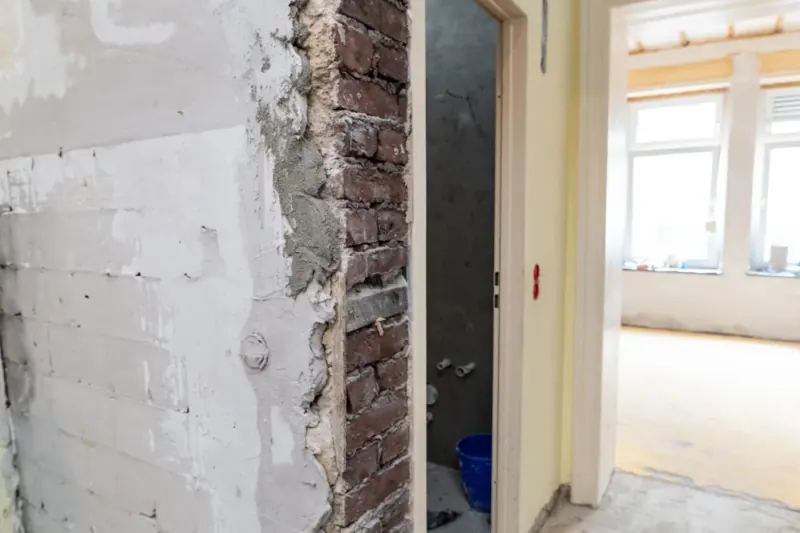 Leere Wohnung während der Sanierung, mit geöffnetem Mauerwerk und hellen Räumen.